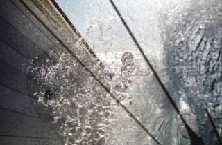 A wall of water crashes over the deck of a yacht in rough seas