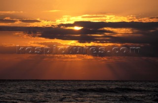 Sun behind clouds at dusk mid Atlantic Ocean