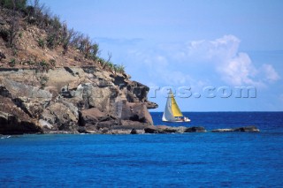 Yacht sailing past headland