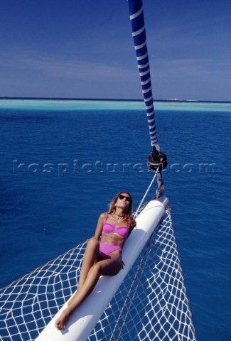 Woman lying on bowsprit of sailing yacht