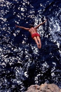 Musto man high diving into the sea from a cliff in Majorca