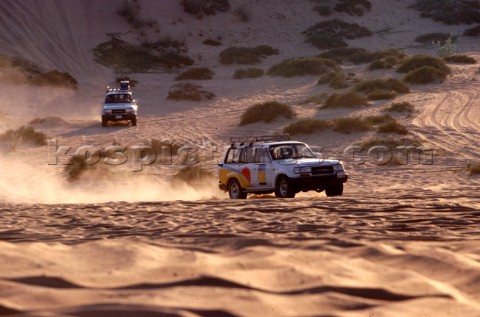 Two trucks drive in convoy through the desert Dubai  United Arab Emirates