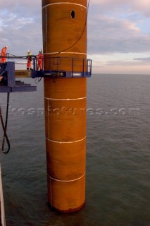 Construction of Windfarm on the Kentish flats in the Thames estuary off Whitstble Kent. Onboard the construction ship Resolution during the foundation process, where the Monopile is hammered in to the seabed with a hydraulic hammer and the transition piece lowered onto the monopile, picture shows monopile being craned into place ready for piling into seabed