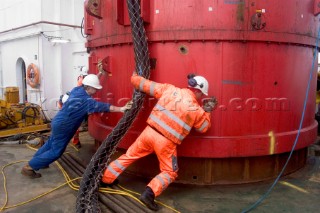 Construction of Windfarm on the Kentish flats in the Thames estuary off Whitstble Kent. Onboard the construction ship Resolution during the foundation process, where the Monopile is hammered in to the seabed with a hydraulic hammer and the transition piece lowered onto the monopile, picture shows monopile being craned into place ready for piling into seabed