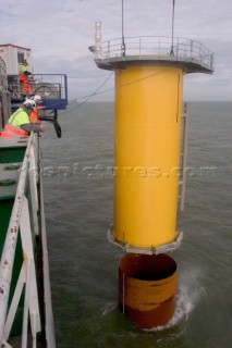 Construction of Windfarm on the Kentish flats in the Thames estuary off Whitstble Kent. Onboard the construction ship Resolution during the foundation process, where the Monopile is hammered in to the seabed with a hydraulic hammer and the transition piece lowered onto the monopile, picture shows monopile being craned into place ready for piling into seabed