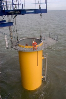 Construction of Windfarm on the Kentish flats in the Thames estuary off Whitstble Kent. Onboard the construction ship Resolution during the foundation process, where the Monopile is hammered in to the seabed with a hydraulic hammer and the transition piece lowered onto the monopile, picture shows monopile being craned into place ready for piling into seabed