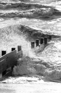 Wave breaking over wooden break-waters.