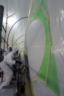 Boatyard workers painting the topsides of a superyacht with a spray gun