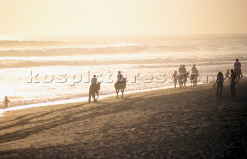 Group of horse riders on sandy beach 