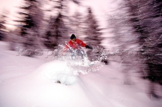 Snowboarder jumps through powder snow.