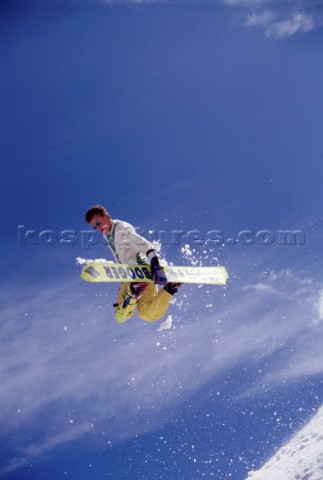 Snowboarder grabs board in mid jump