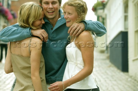 A man and two girls embrace on a cobbled street in Lymington UK
