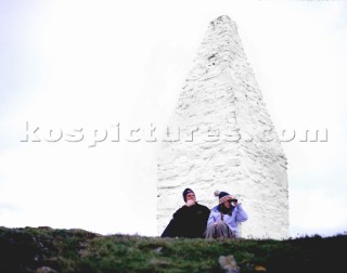 Couple looking out to sea from white harbour marker, Porthgain harbour, Pembrokeshire, Wales