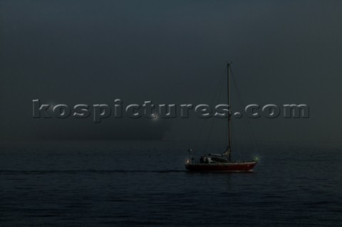 Cruising yacht motoring under power on a calm sea at night showing navigation lights on a collision 