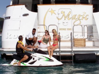 Man on jet ski and guests on aft platform of superyacht Magic