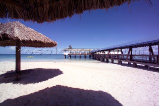 Sun shades and pier on sandy beach