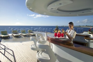 Superyacht stewardess preparing drinks at bar on deck