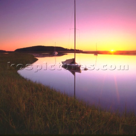 Sailing boat moored on still water at sunset