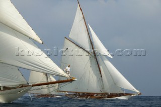 Crew member on bowsprit of classic yacht racing in fleet
