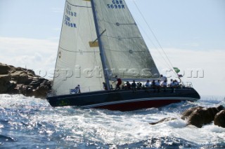 Swan yacht sailing through small gap in passing very close to rocks