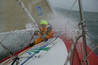 Skipper of the Open 60 Ocean yacht Alex Thomson working on a wet foredeck in rough seas