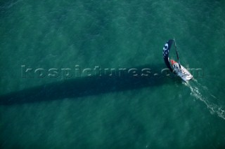 Aerial view of long shadow cast from Open 60 sailing yacht over calm sea