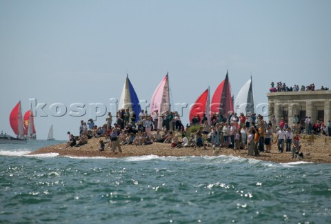 The Fasntet fleet pass through the Solent by Hurst Castle watched by a crowd on the beach