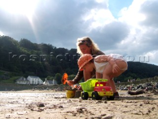 Young girl toddler playing with her mother on a sandy beach