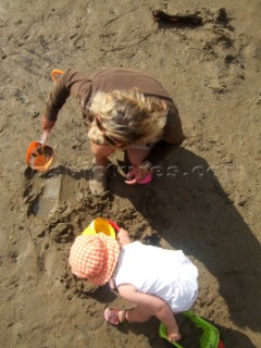 Young girl toddler playing with her mother on a sandy beach