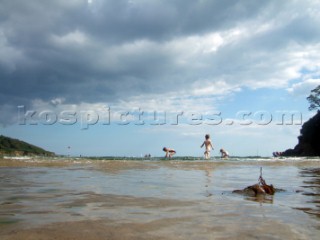 Children playing and paddling on a sandy beach looking for crustacea and crabs