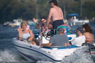 Family with older people on holiday in a speedboat waving with joy