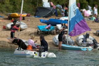 Couple with black dog driving tender into shore