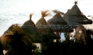 Straw sun shades on a beach at sunset