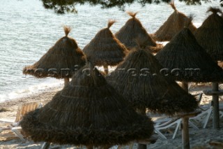 Straw sun shades on a beach at sunset