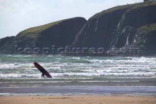 Surfer with long board heads into the water