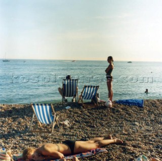 People and deckchairs on pebble beach, Brighton