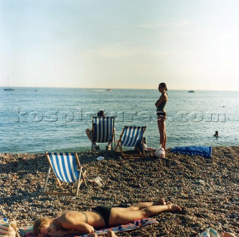 People and deckchairs on pebble beach Brighton