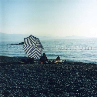 Couple under umbrella on pebble beach