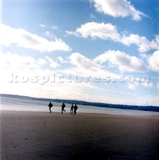 People running along wet sand on the beach at Swansea, Wales