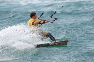 Kitesurfer carving through wave in strong winds