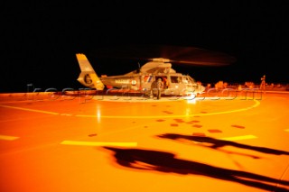 French Navy Coastguard helicopter on helipad. Men in survivial suits on deck of supertanker.