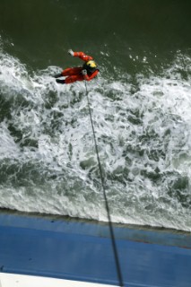 Coastguard Rescue Worker on end of line running from Helicoptor by side of ship