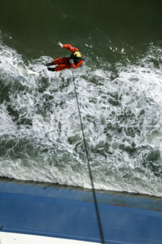 Coastguard Rescue Worker on end of line running from Helicoptor by side of ship