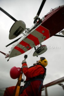 Underside view of Coastguard Helicopter shot from yacht being aided with Rescue worker aboard