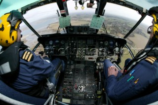 Coastguard Helicopter Cockpit with Pilot and Co-pilot looking at view over land and sea taken with fish eye lens