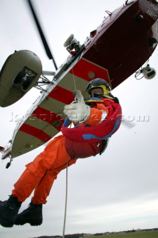 Coastguard rescue worker being lowered from helicopter by winch from below