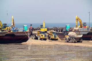 two barges with beach infill unloading there cargo at the low water line, Sea defence building in whitstable kent raising the level of the beach some meters to counter rising sea level and erosion