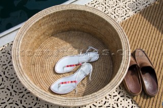 Sandals and deck shoes by a basket and matt on the dock