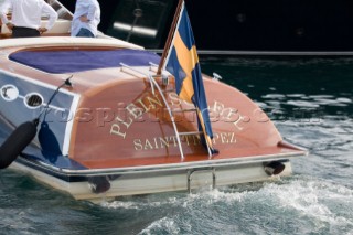 Polished varnished wood on the stern of a classic wooden Riva tender for a superyacht with ensign