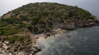 Aerial view of a lone dinghy nestling on a sandy beach of an island